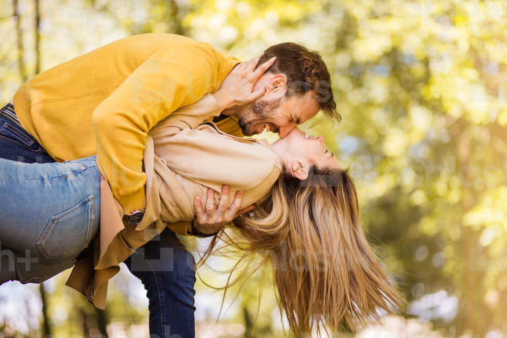 A Couple Kissing In The Park Background