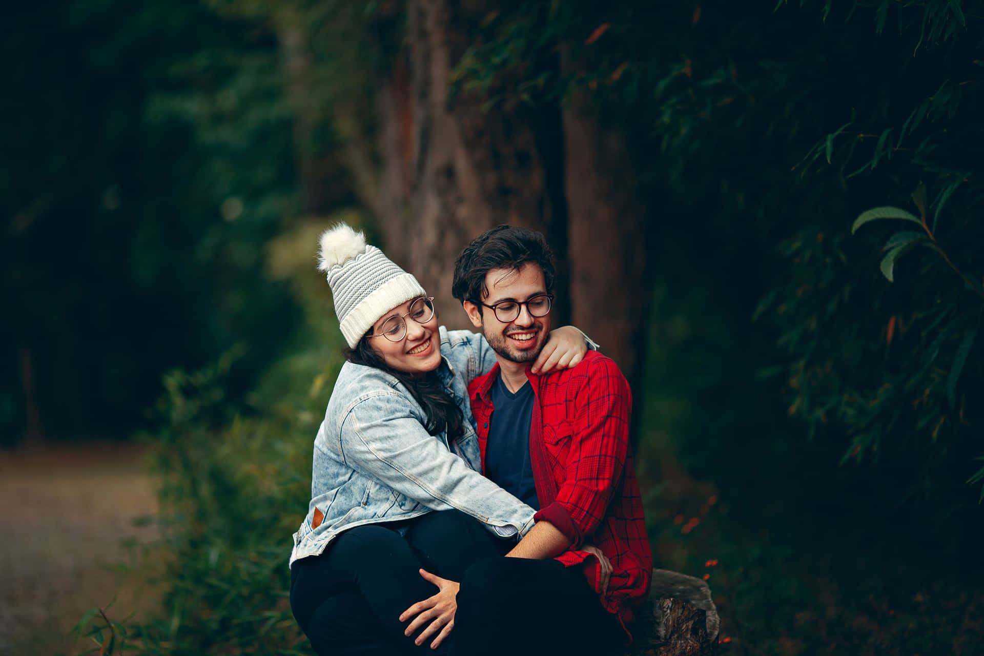 A Couple Sitting On A Log In The Woods