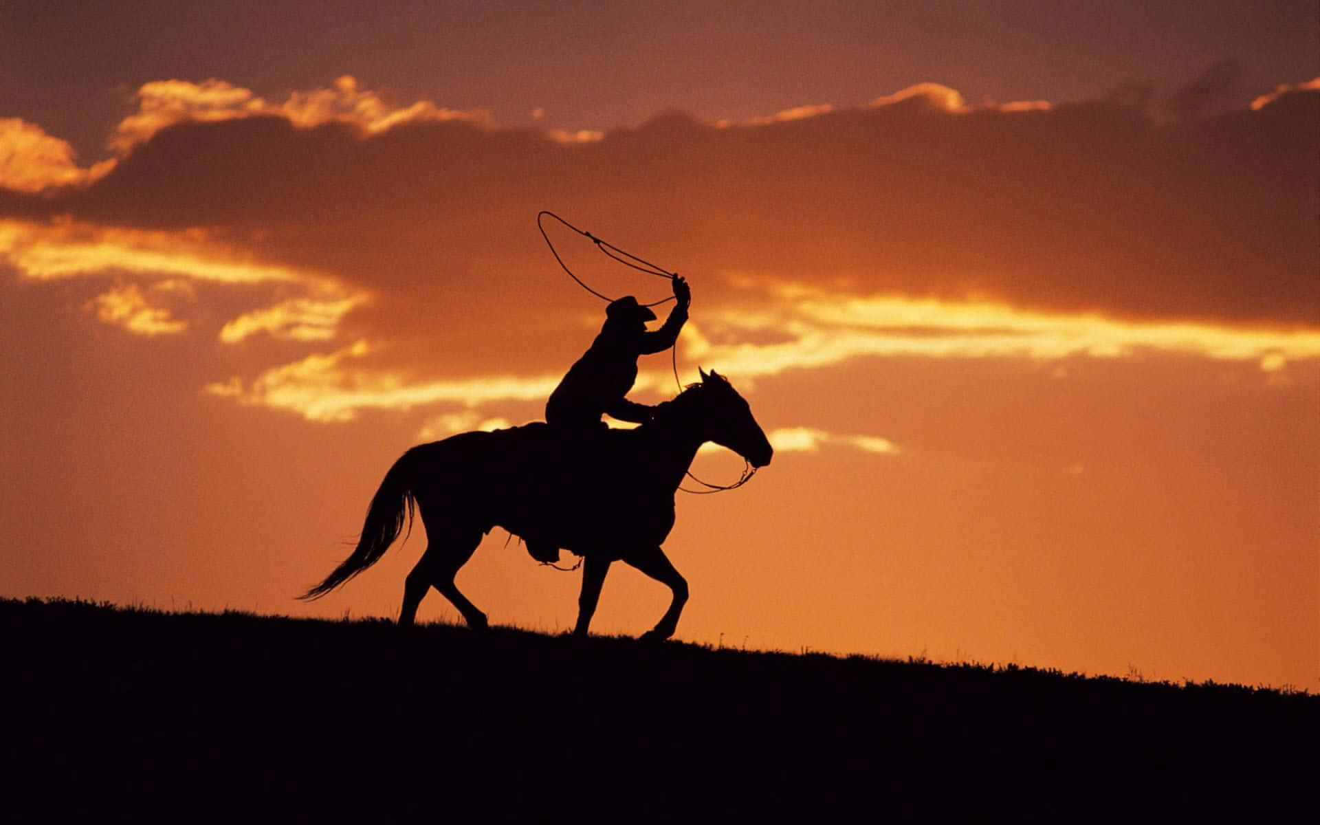 A Cowboy On A Horse Is Silhouetted At Sunset Background