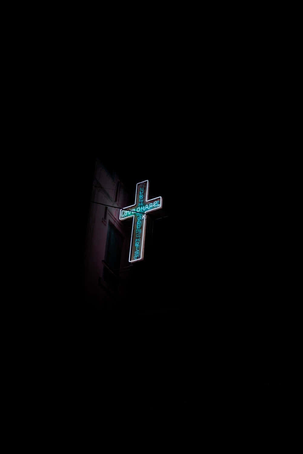 A Cross Is Lit Up In The Dark Background