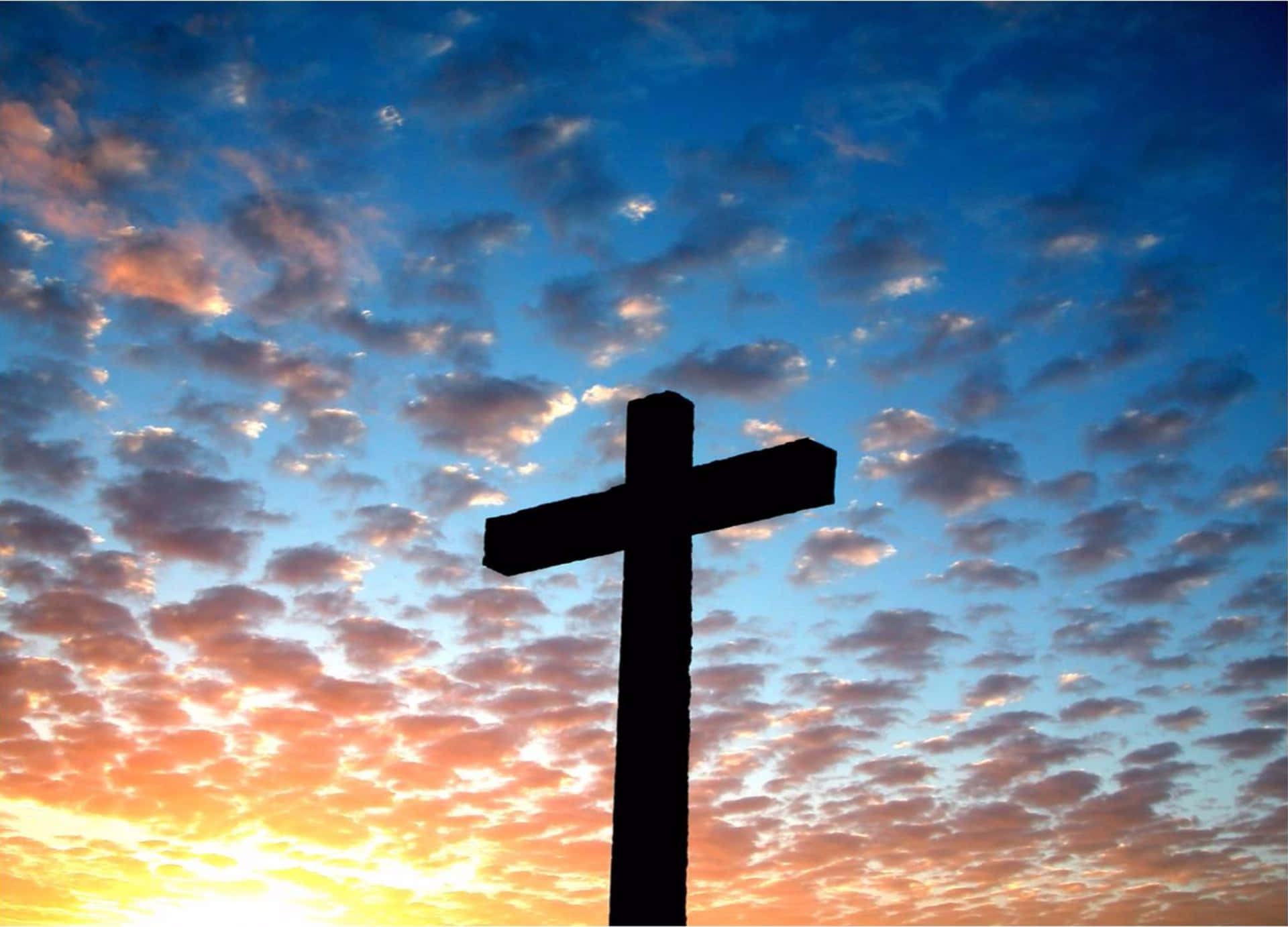 A Cross Is Silhouetted Against A Sunset Sky Background