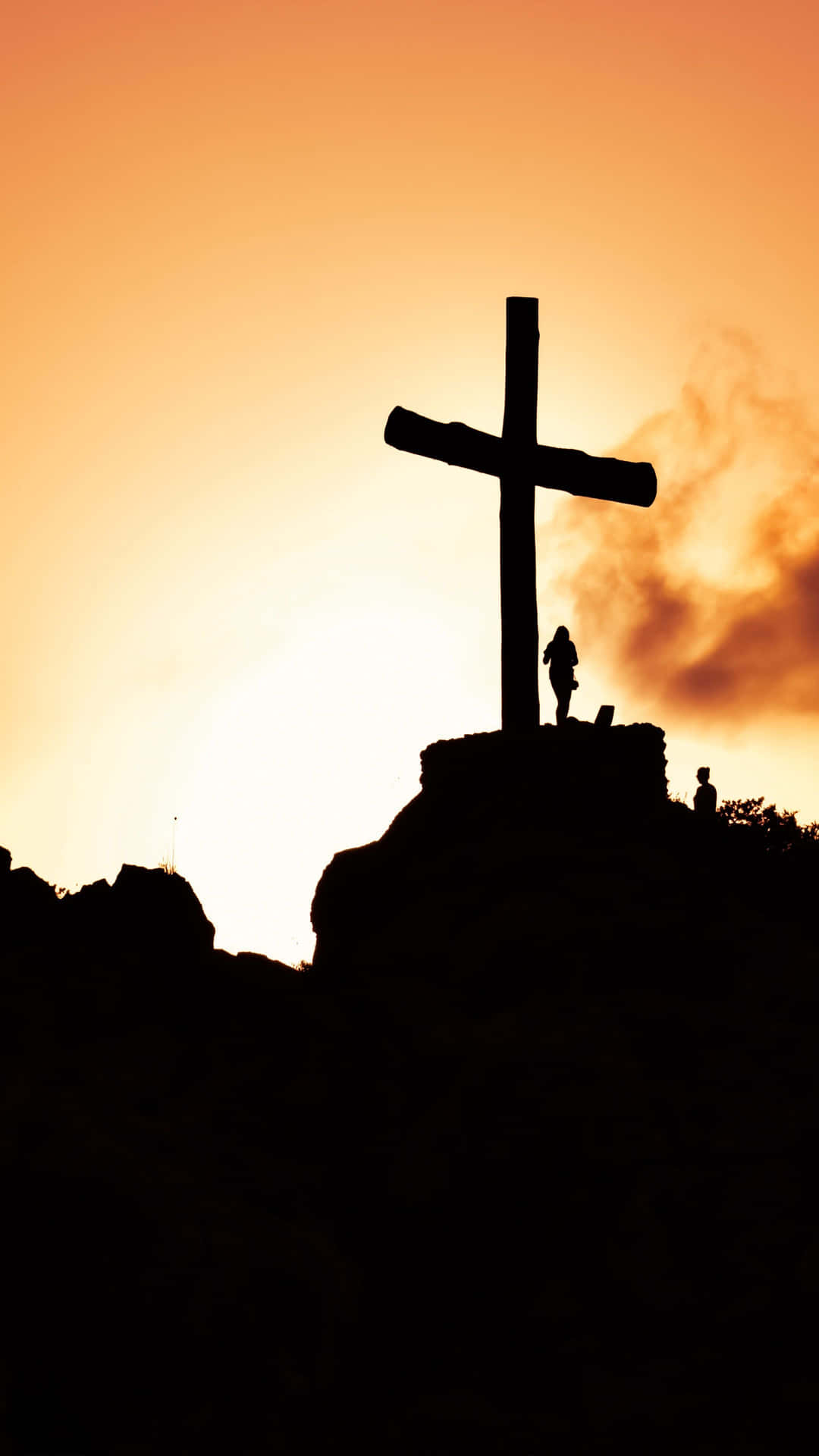 A Cross Is Silhouetted Against The Sunset Background