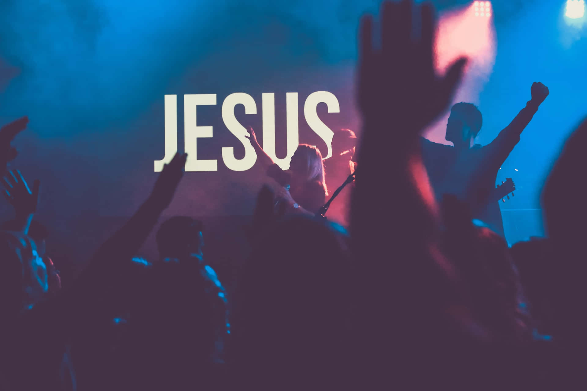 A Crowd Of People At A Concert With The Word Jesus Background