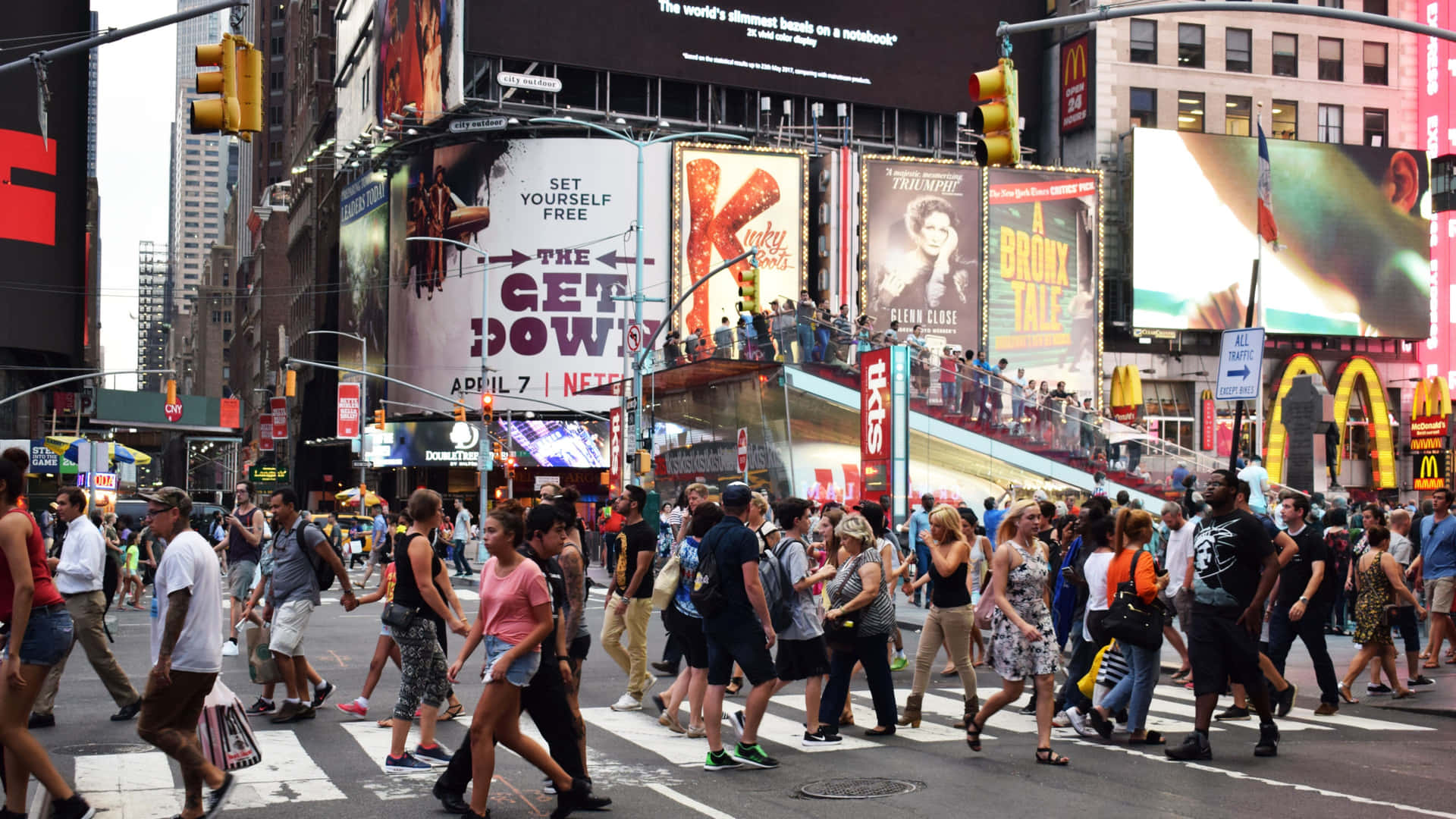 A Crowd Of People Crossing A Busy Street In Times Square Background