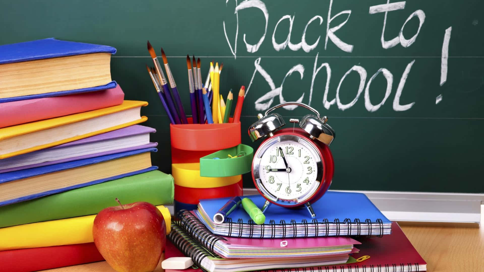 A Desk With Books, Pencils, And An Alarm Clock Background