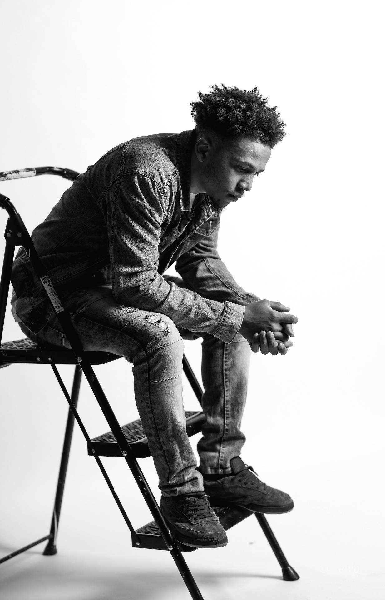 A Detailed Portrait Of An Insightful Black Man Perched On A Stepladder Background