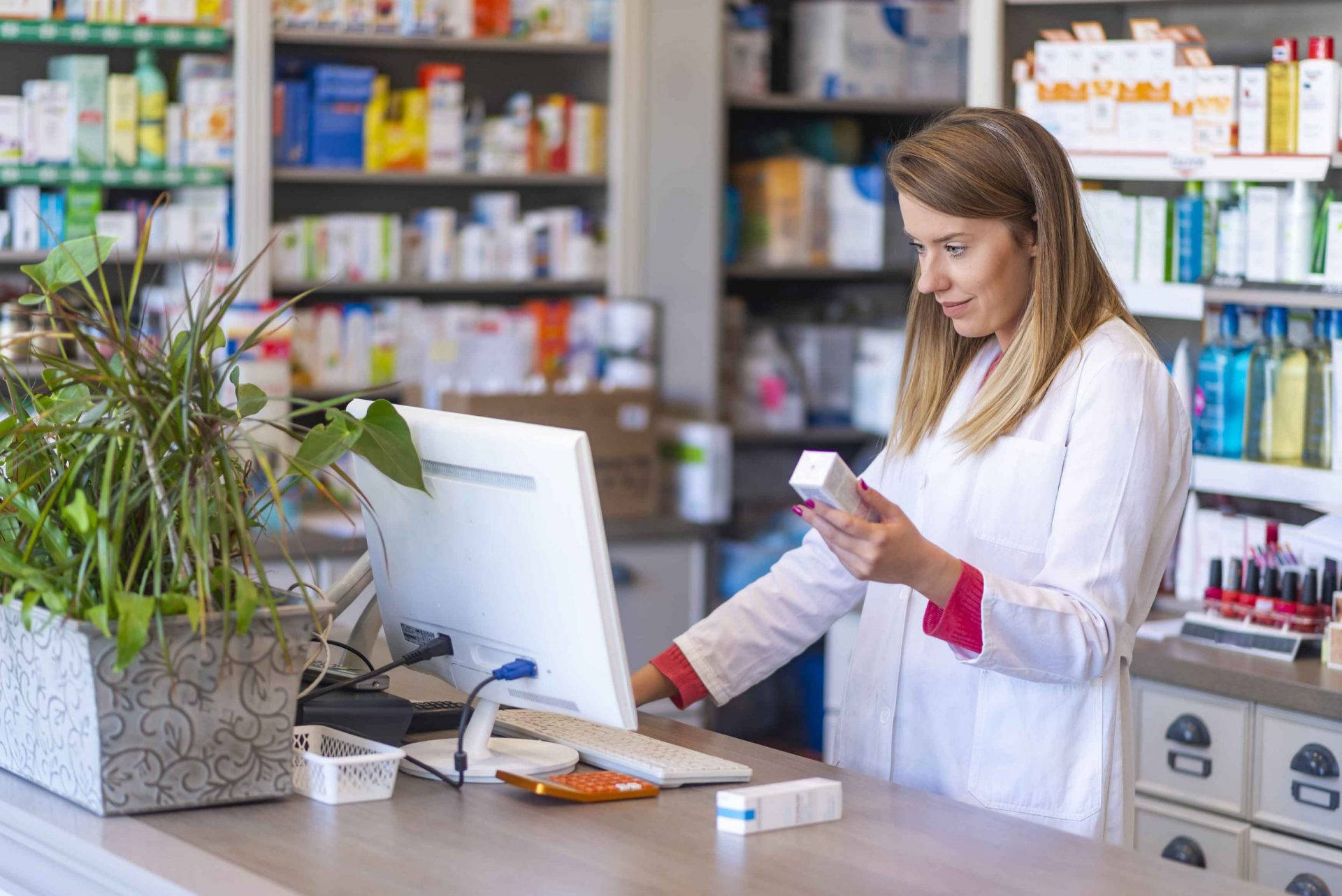 A Diligent Female Pharmacist Perusing Medication In A Pharmacy Background