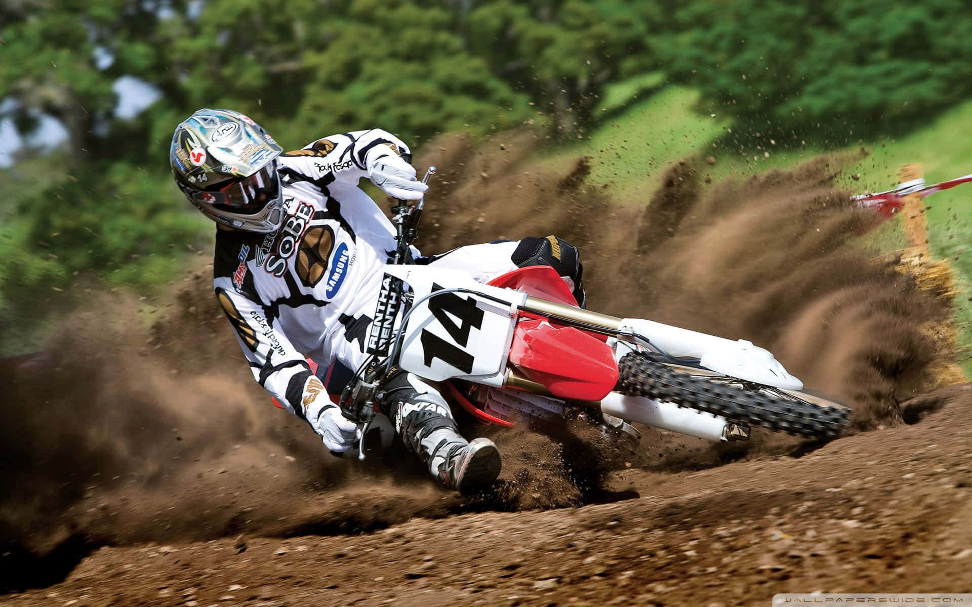 A Dirt Bike Rider Is Riding His Bike On A Dirt Track Background