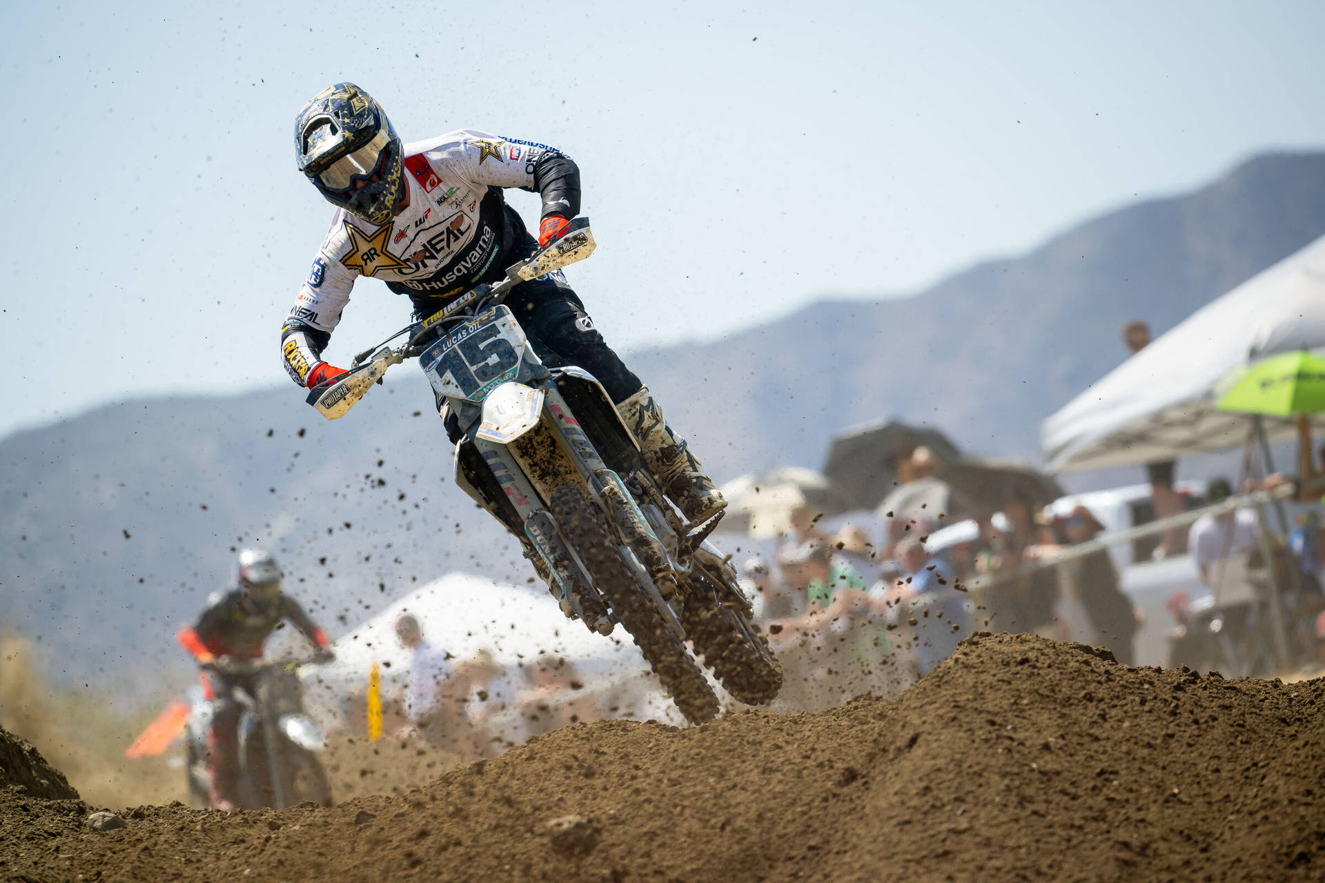 A Dirt Bike Rider Is Riding His Bike On A Dirt Track Background