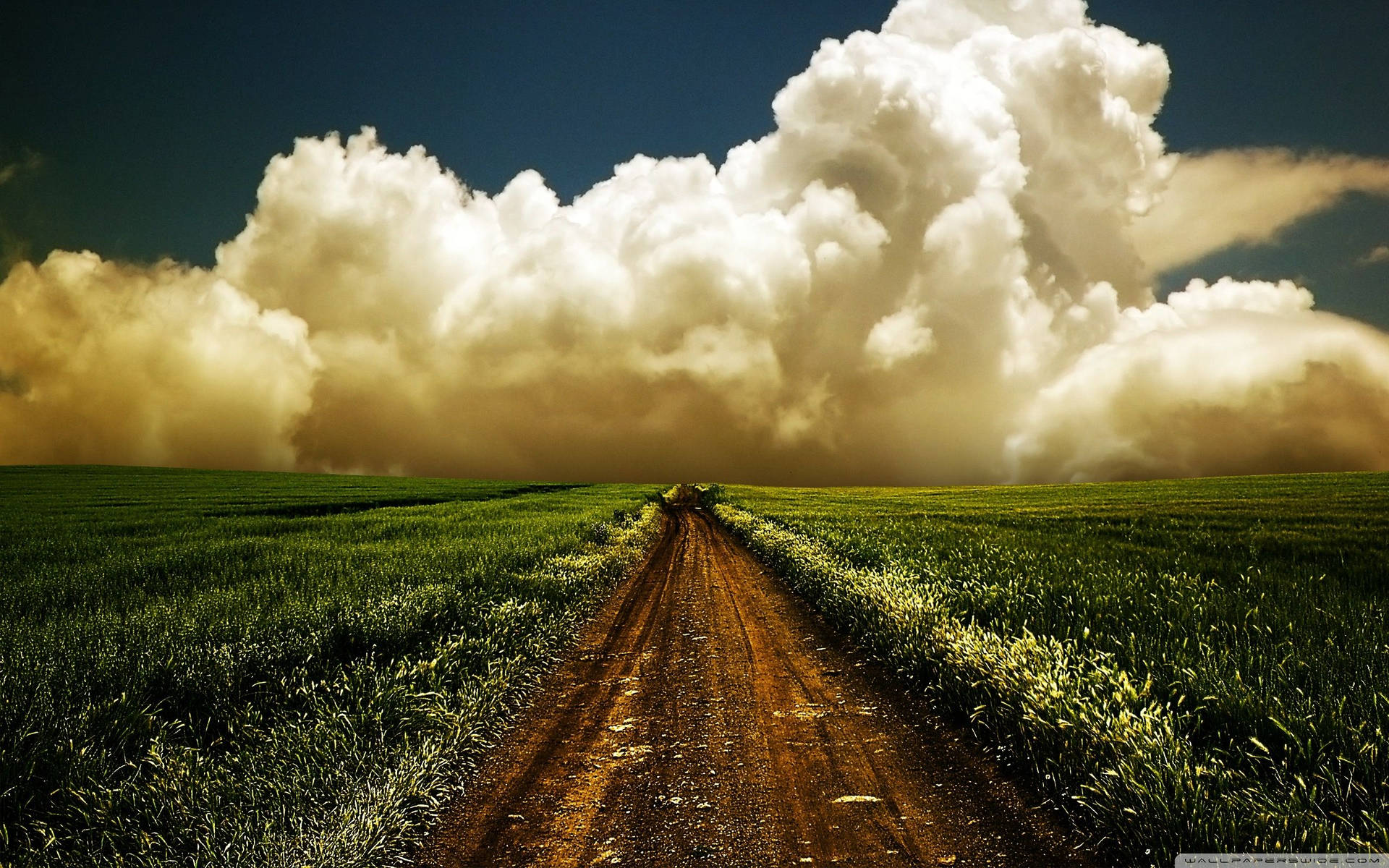 A Dirt Road With Clouds In The Sky Background