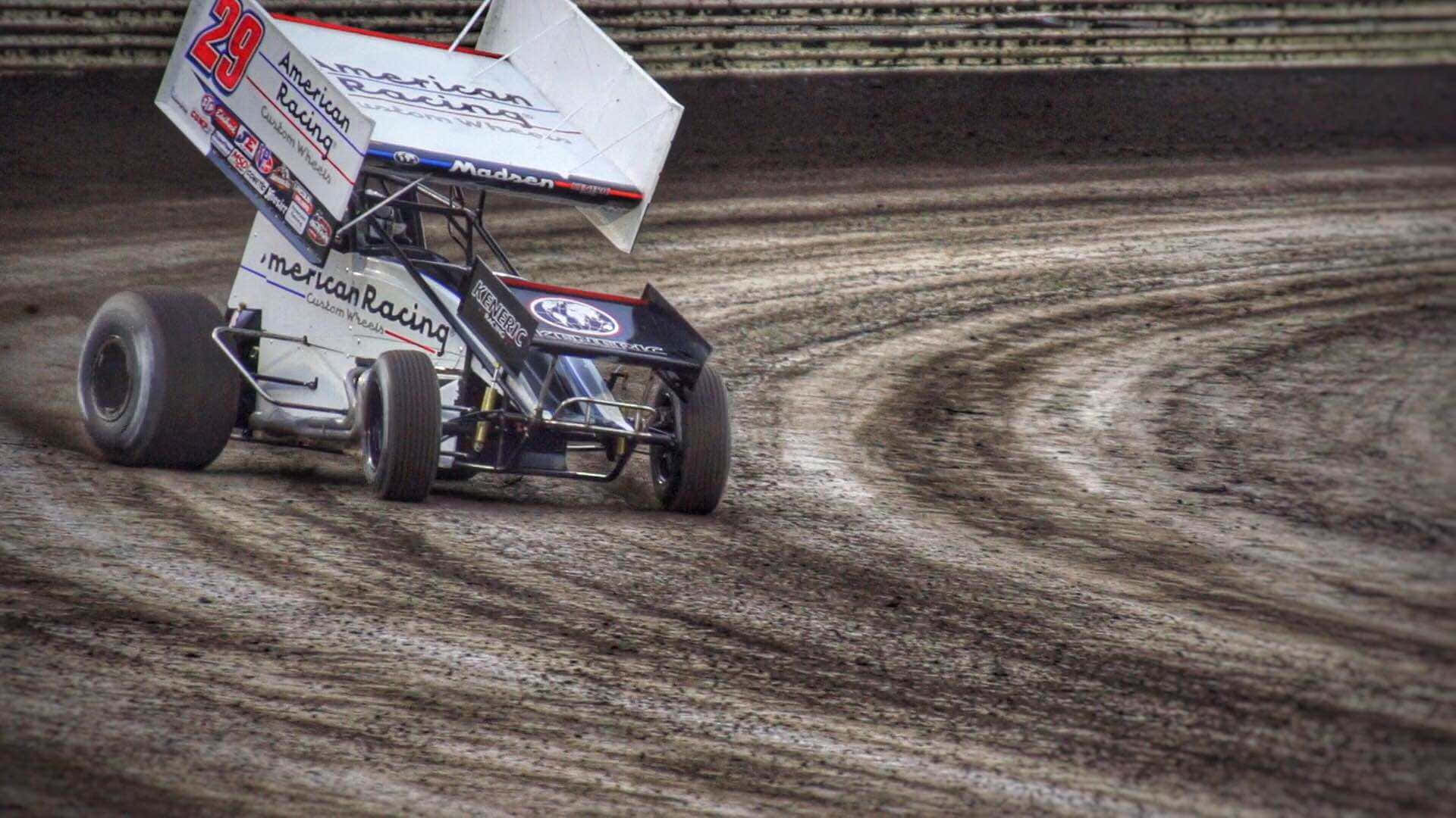 A Dirt Track Race Car Driving Down The Track Background