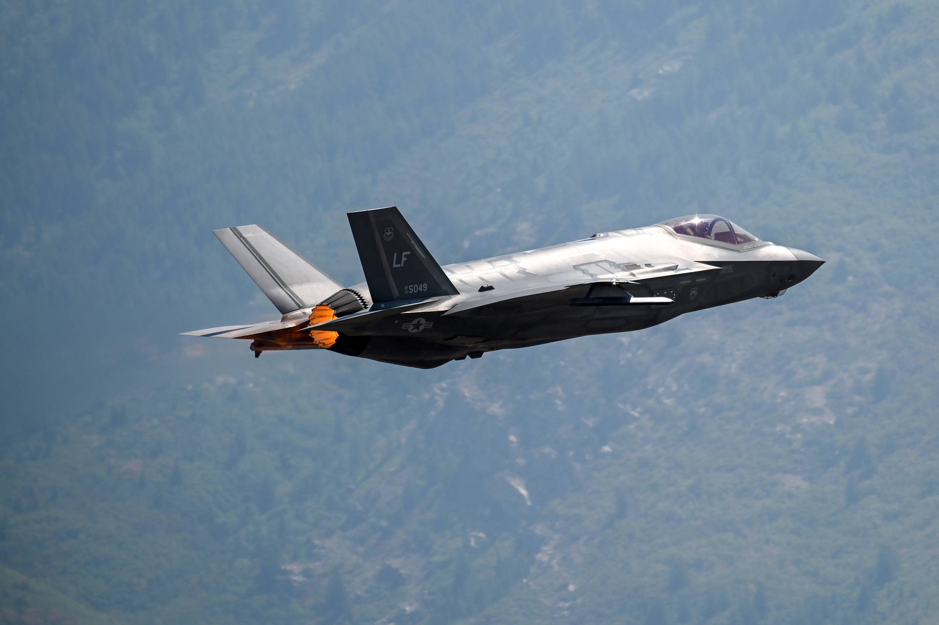 A F-15 Fighter Jet Flying Over A Mountain Background