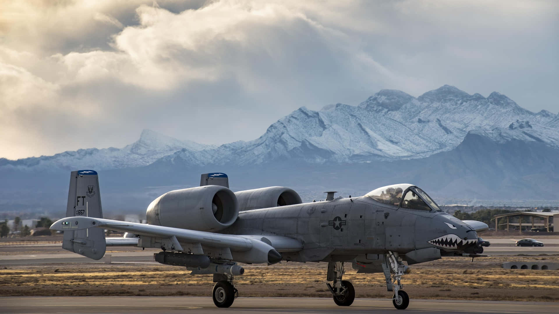 A F-16 Aaa Aircraft On The Runway With Mountains In The Background Background