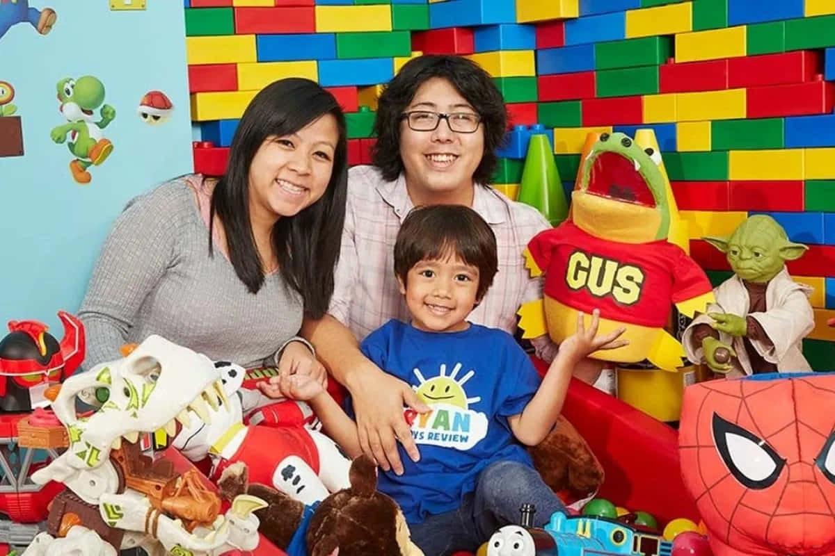 A Family Poses With A Child And Stuffed Toys Background