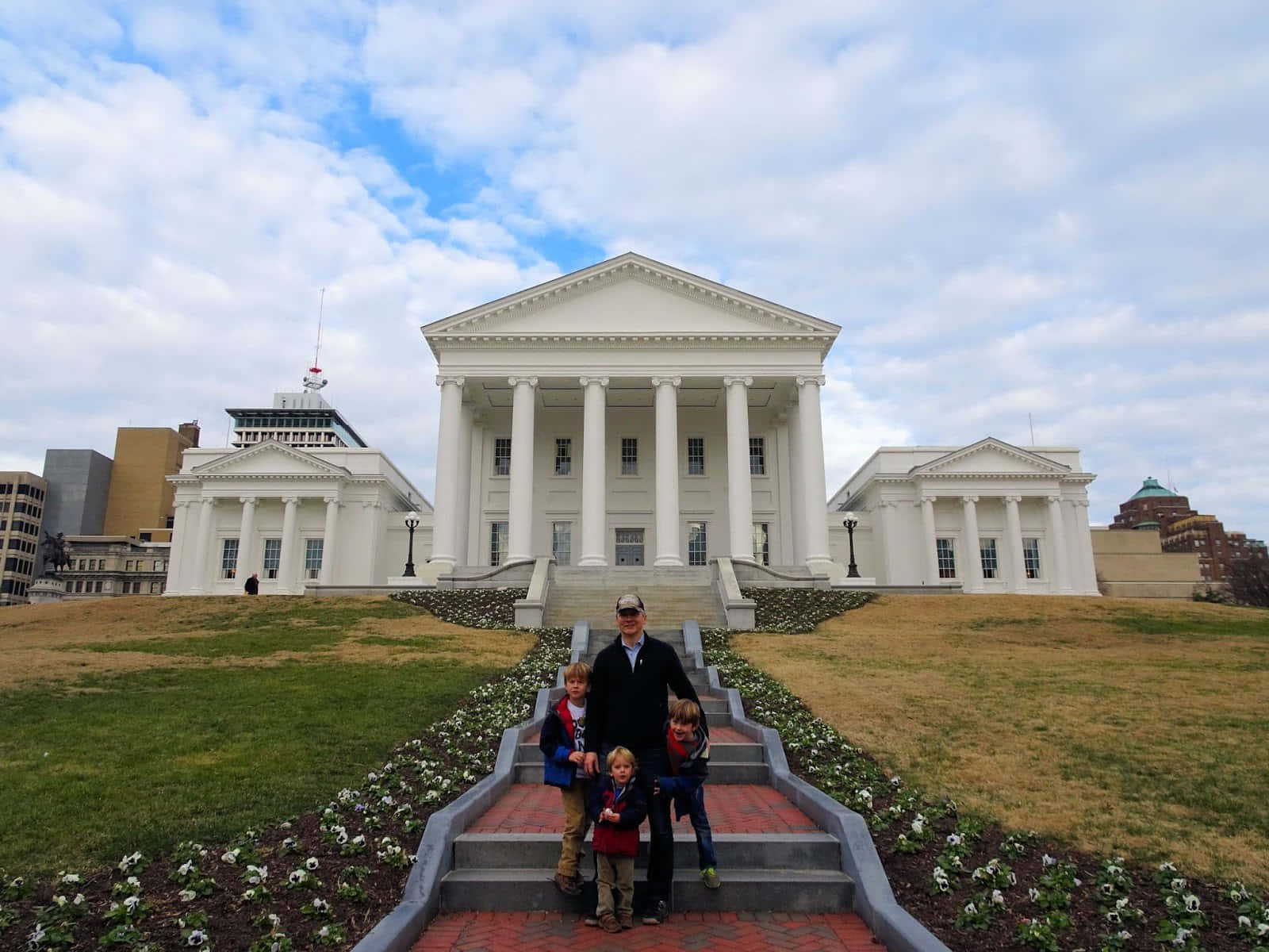 A Family Posing In Front Of The Virginia State Capitol Background