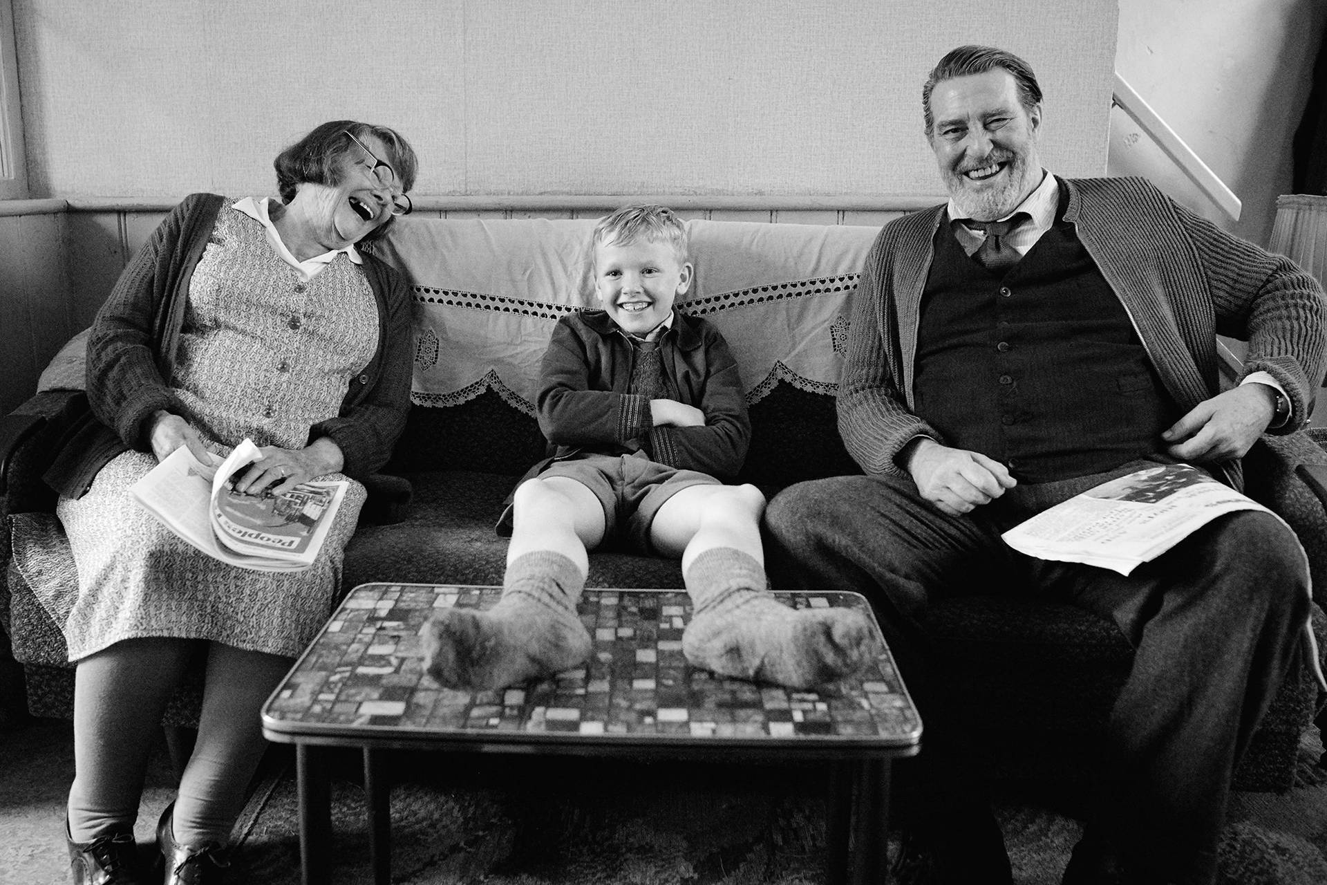 A Family Sitting On A Couch With A Young Boy