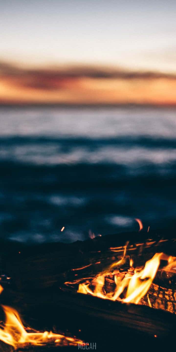 A Fire Pit With Flames On The Beach Background