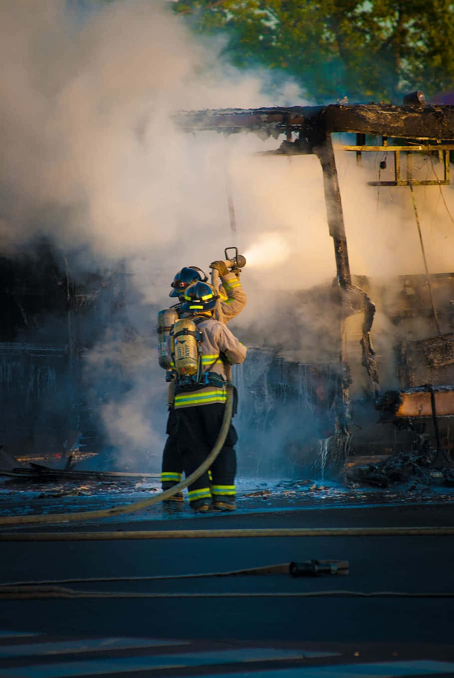 A Firefighter Is Battling A Fire Background