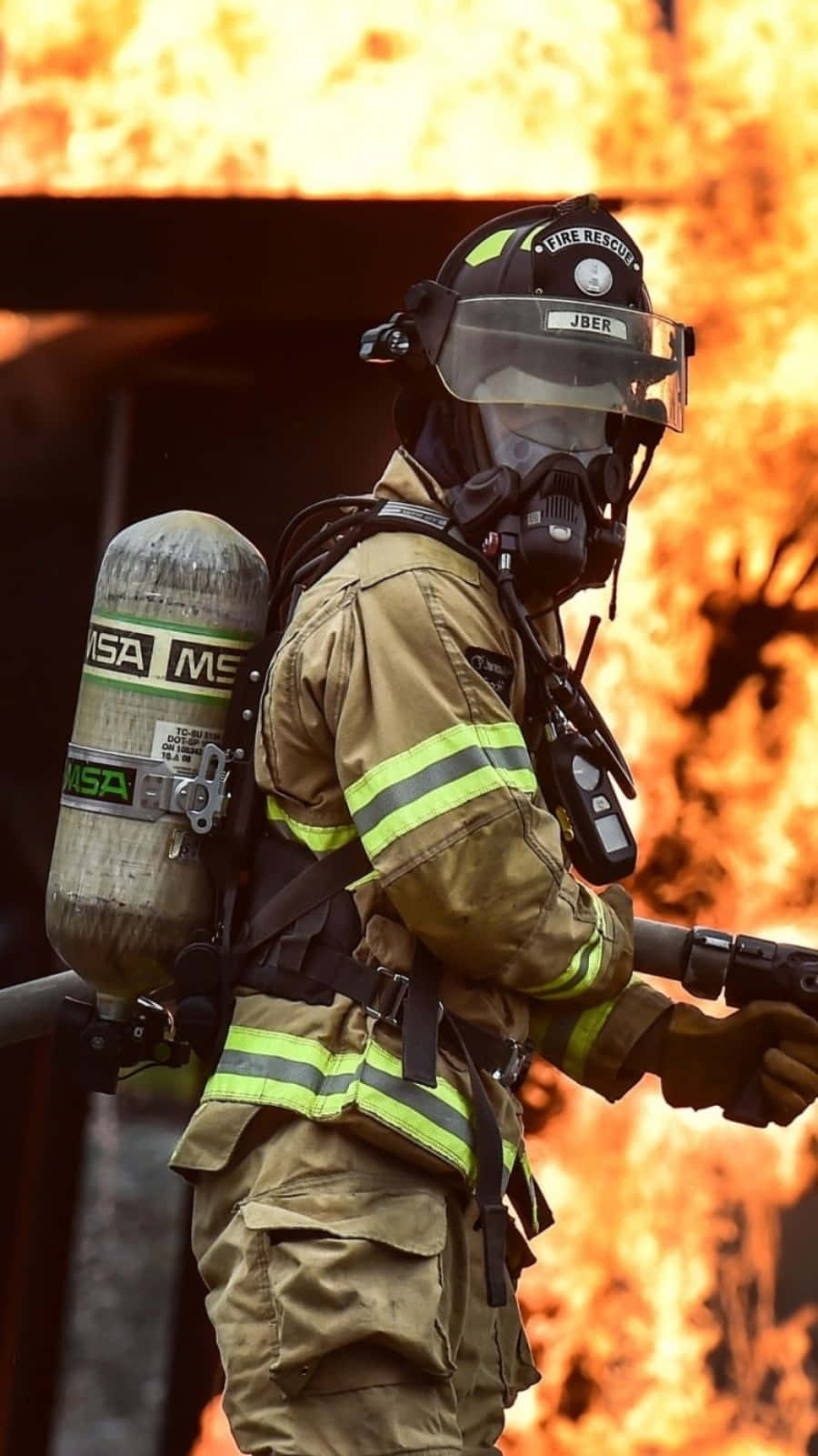 A Firefighter Is Holding A Hose In Front Of A Fire Background