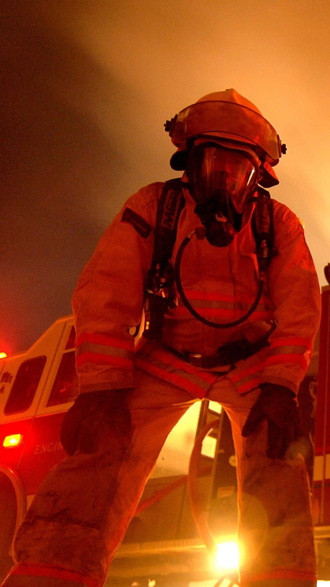 A Firefighter Standing In Front Of A Fire Truck Background