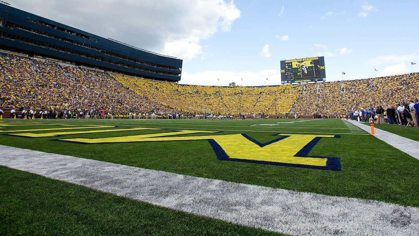 A Football Field With A Large Crowd Watching A Game Background