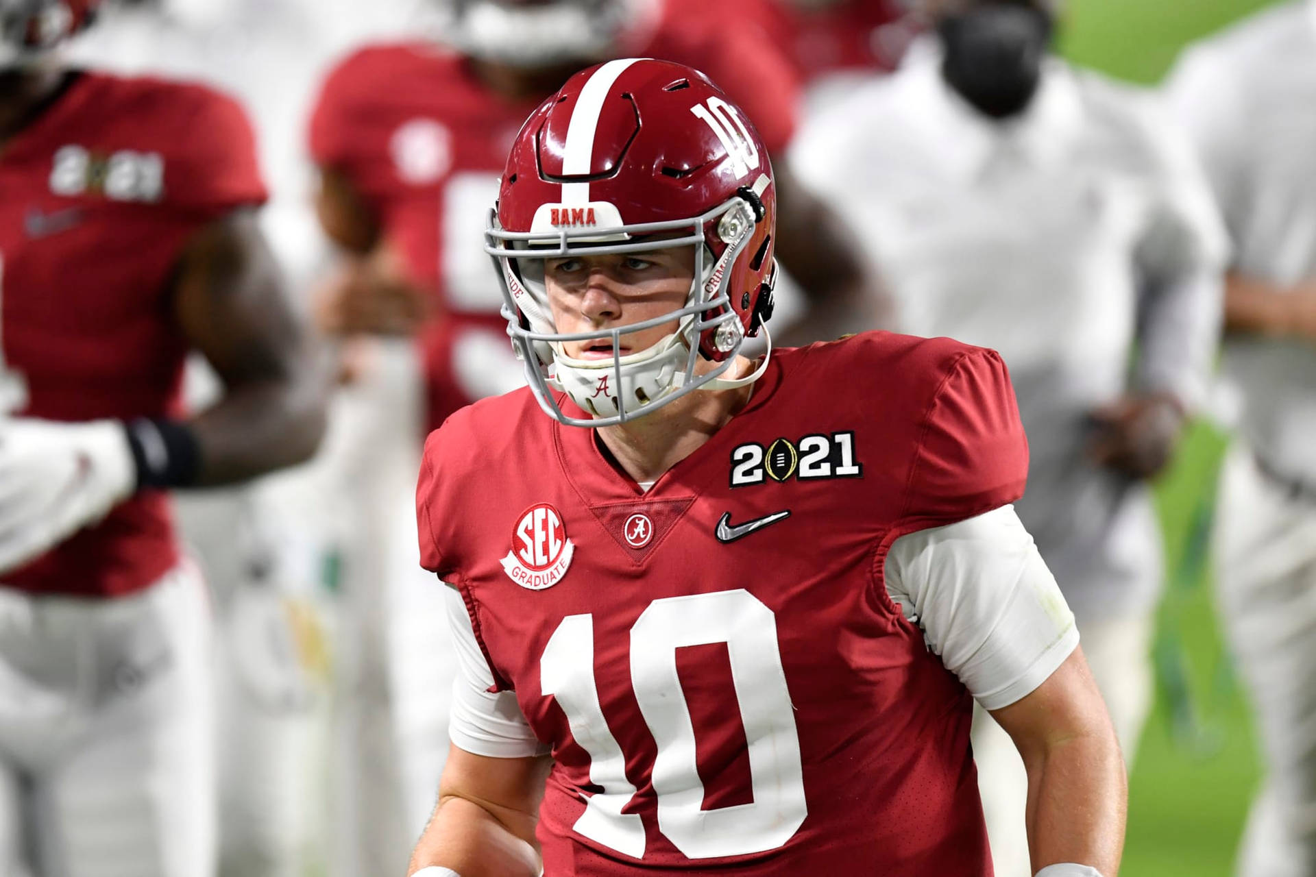 A Football Player Is Walking On The Field Background