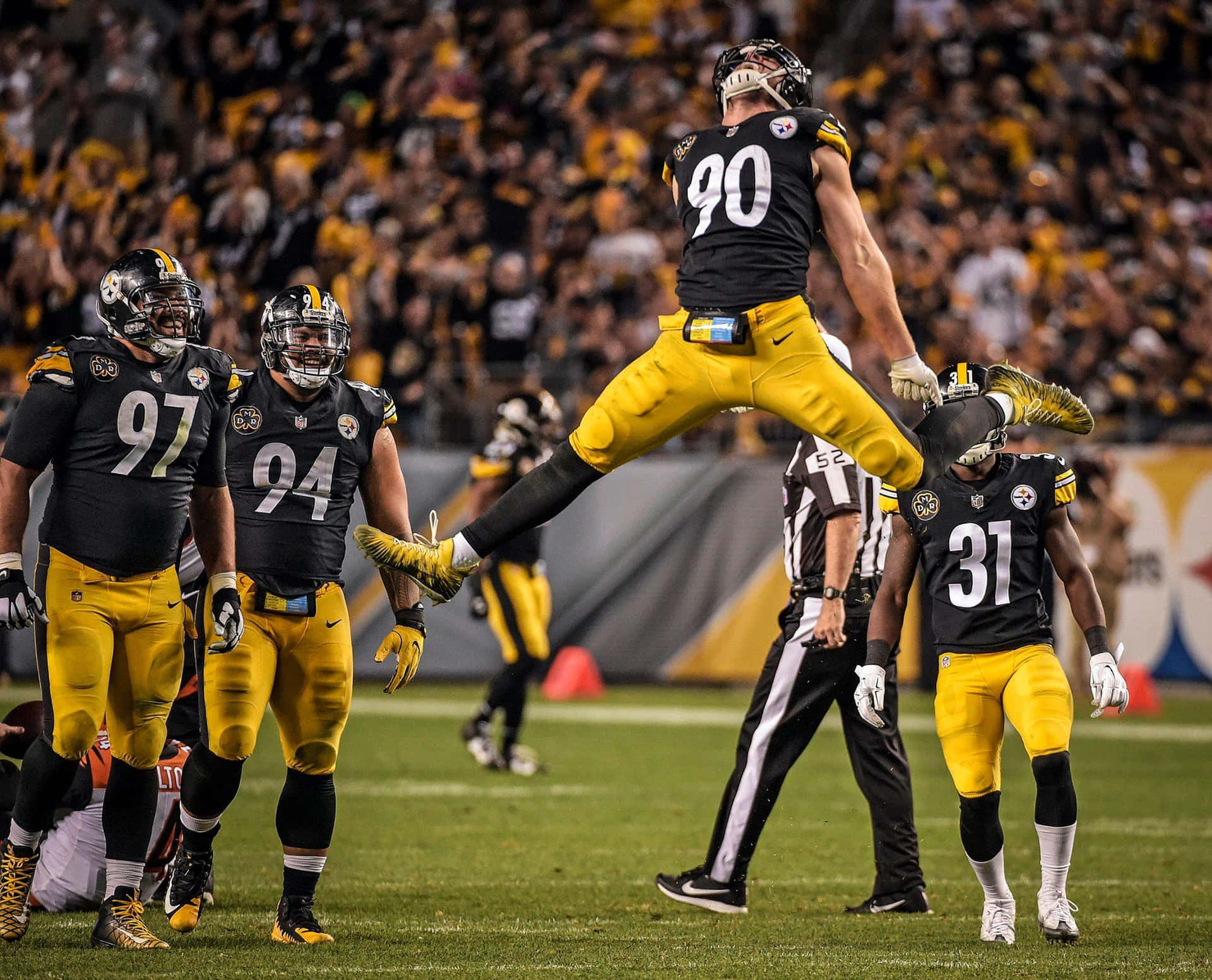 A Football Player Jumping In The Air While Others Watch Background