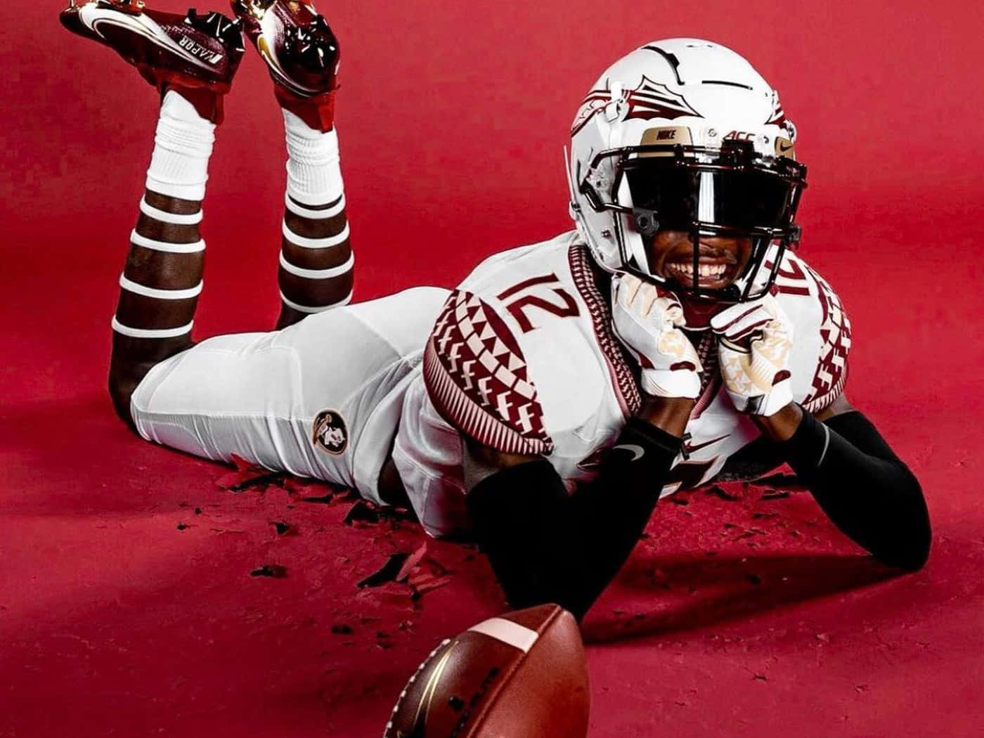 A Football Player Laying On The Ground With His Helmet On Background