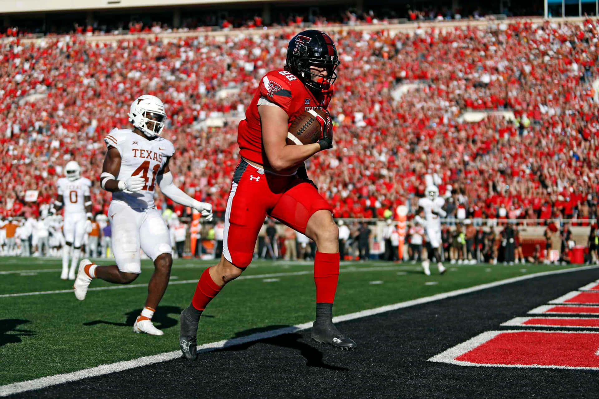 A Football Player Running With The Ball In His Hands Background