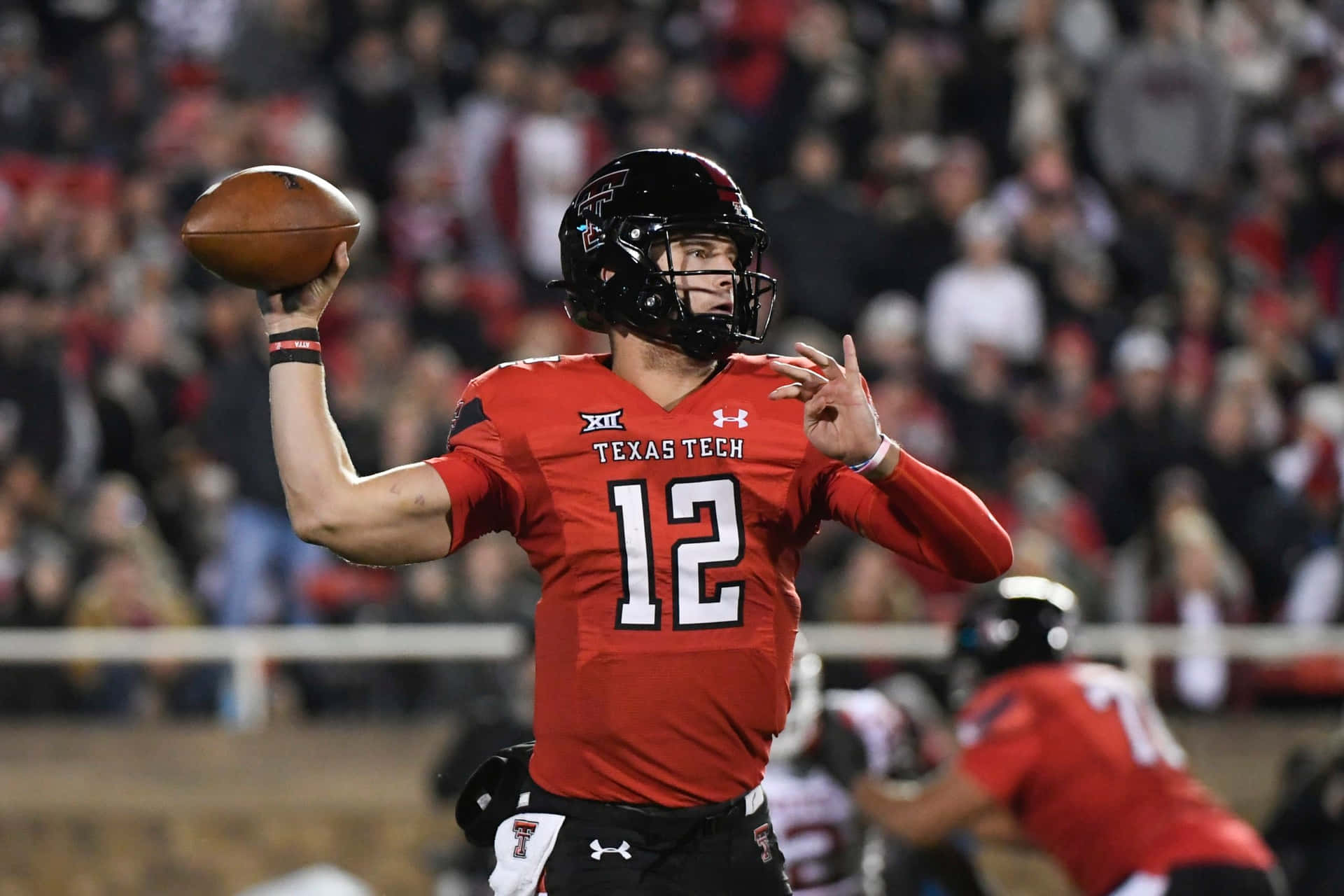 A Football Player Throwing A Ball In A Game Background