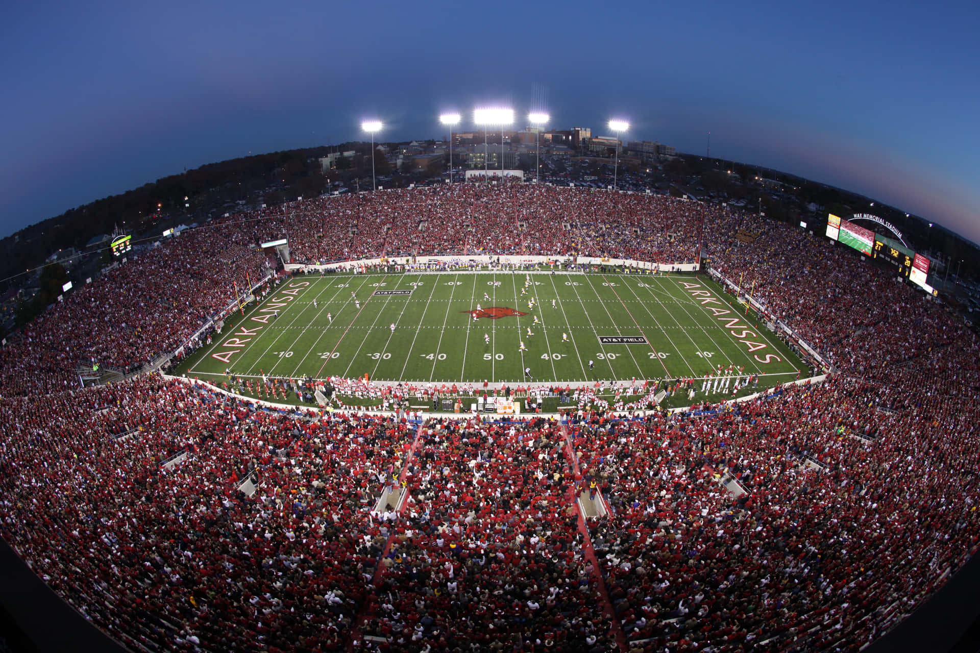 A Football Stadium With A Large Crowd At Night Background