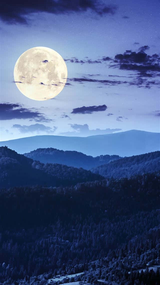 A Full Moon Rising Over A Mountain Background