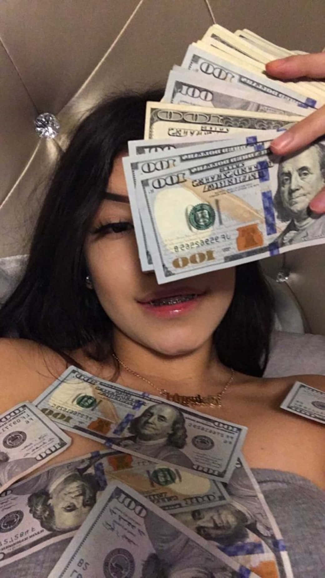 A Girl Laying On A Bed With A Bunch Of Money