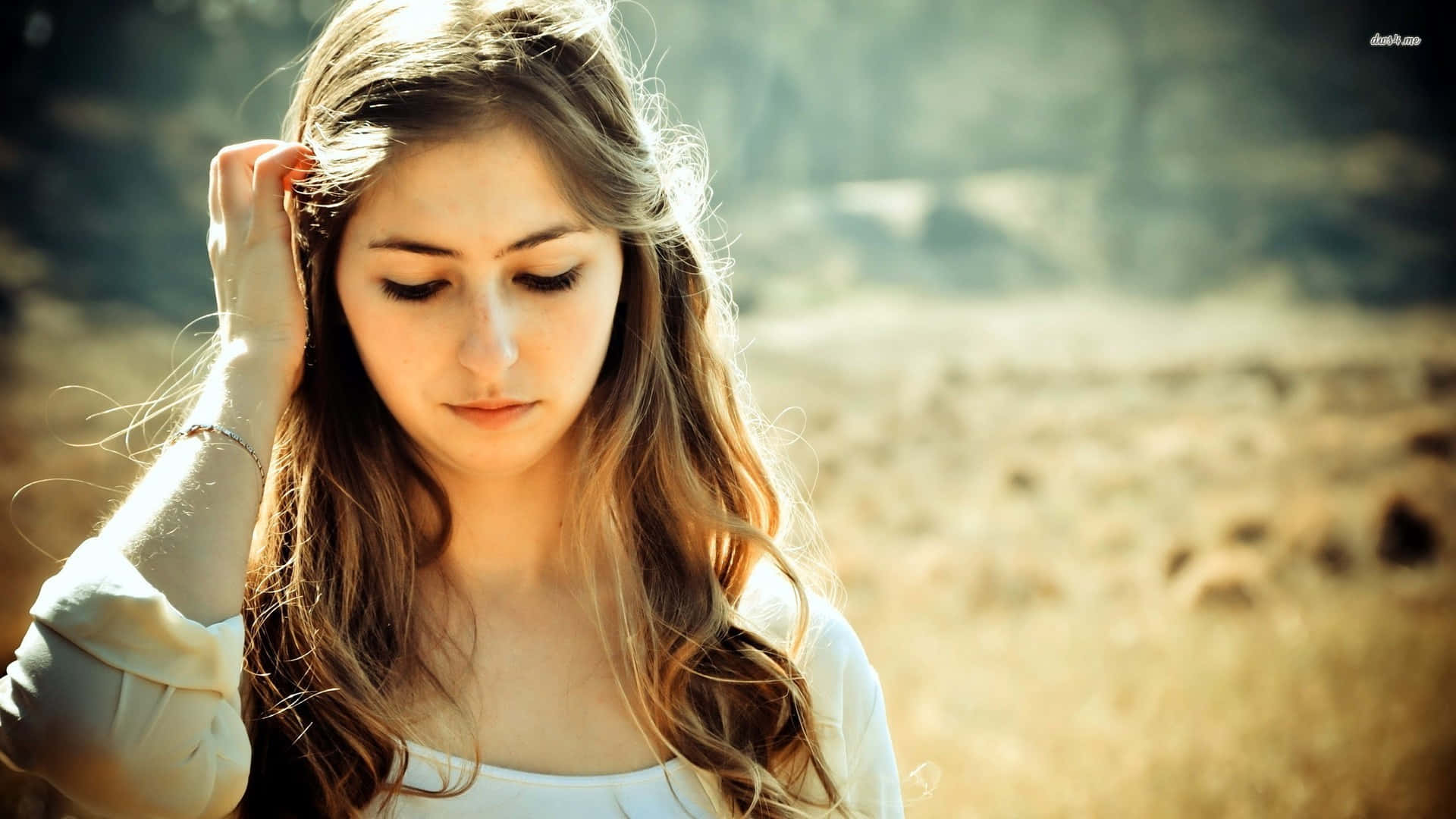 A Girl With Her Head Down In A Field Background