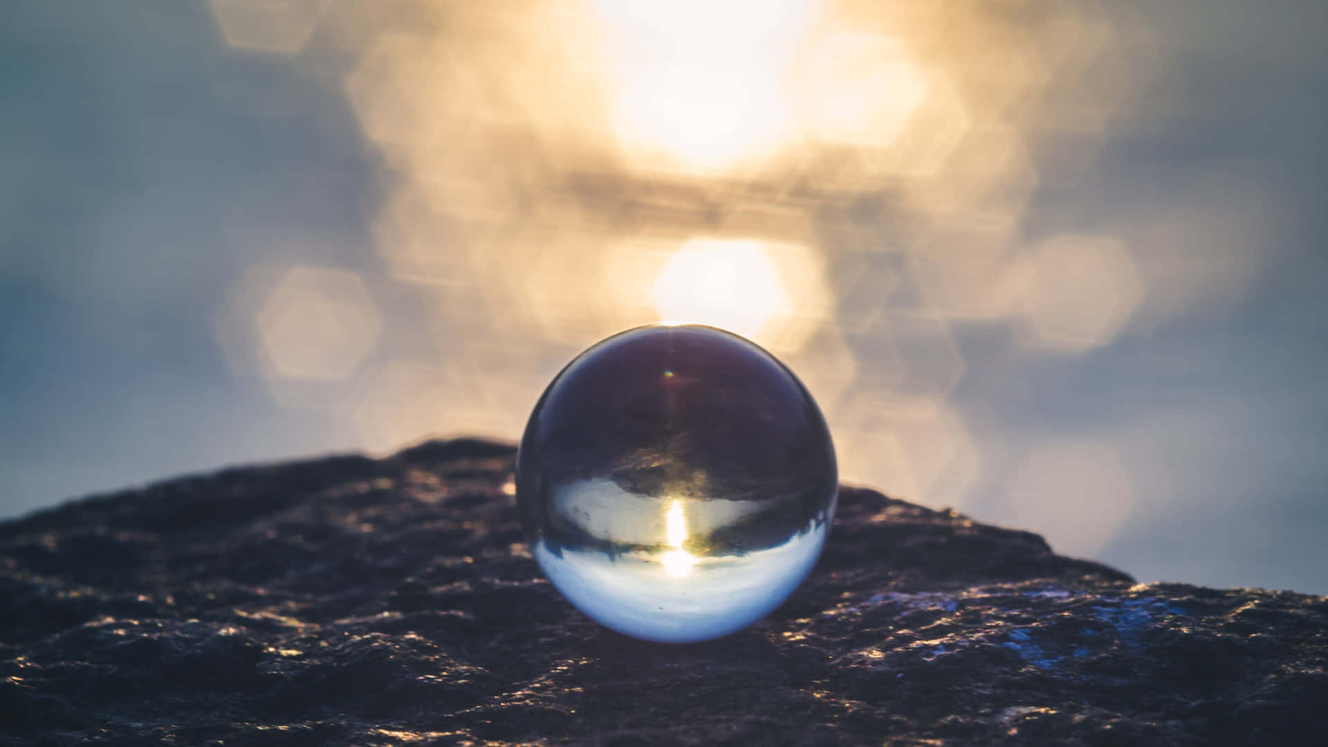 A Glass Ball Sitting On Top Of A Rock Background