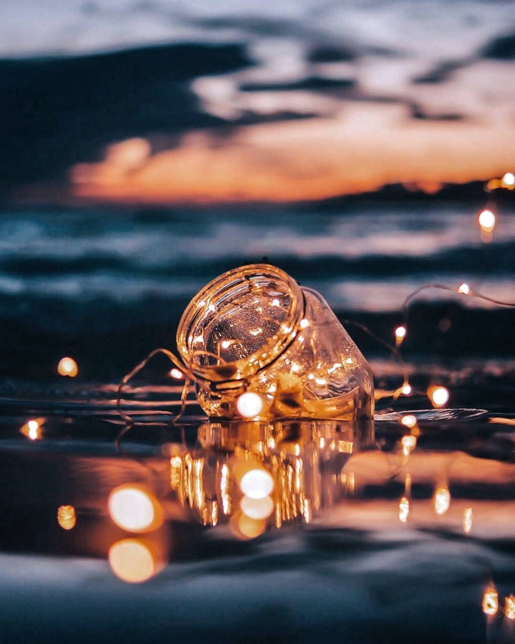 A Glass Jar With Lights Floating In The Water Background