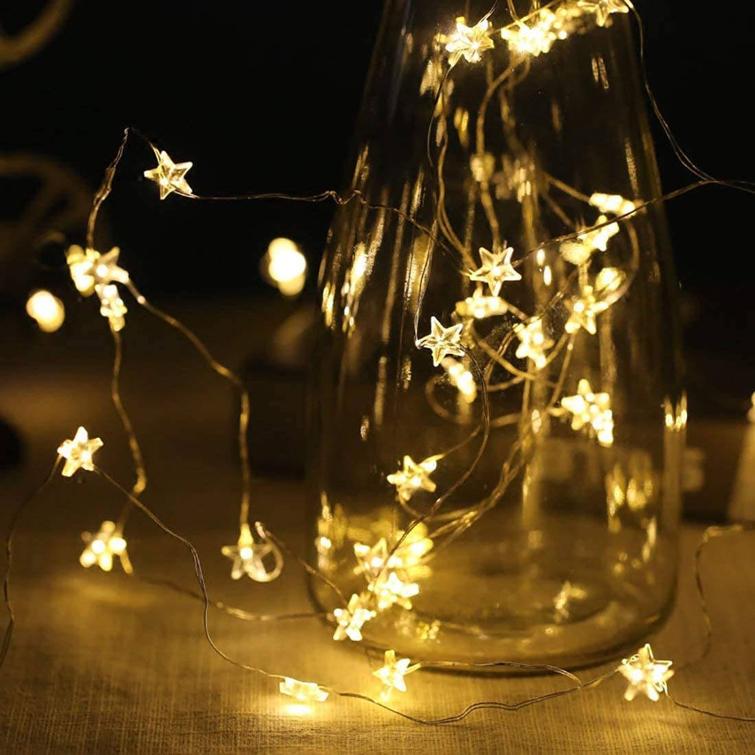 A Glass Vase With A Star String Light Background