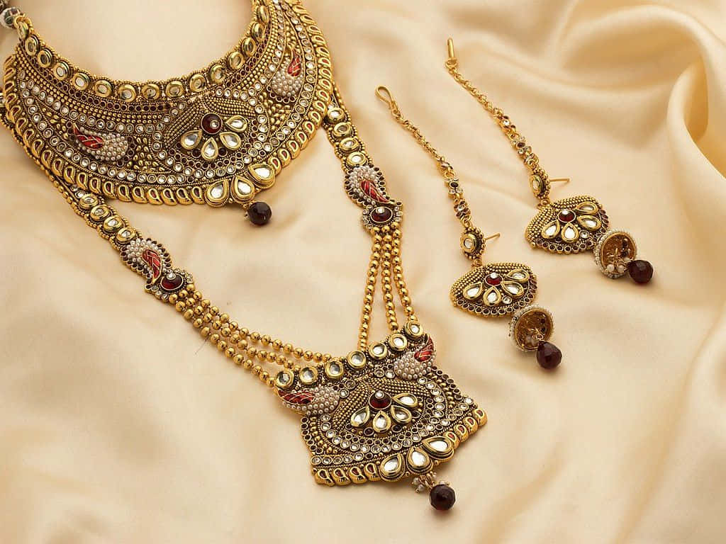 A Gold And Red Jewelry Set With A Necklace And Earrings Background