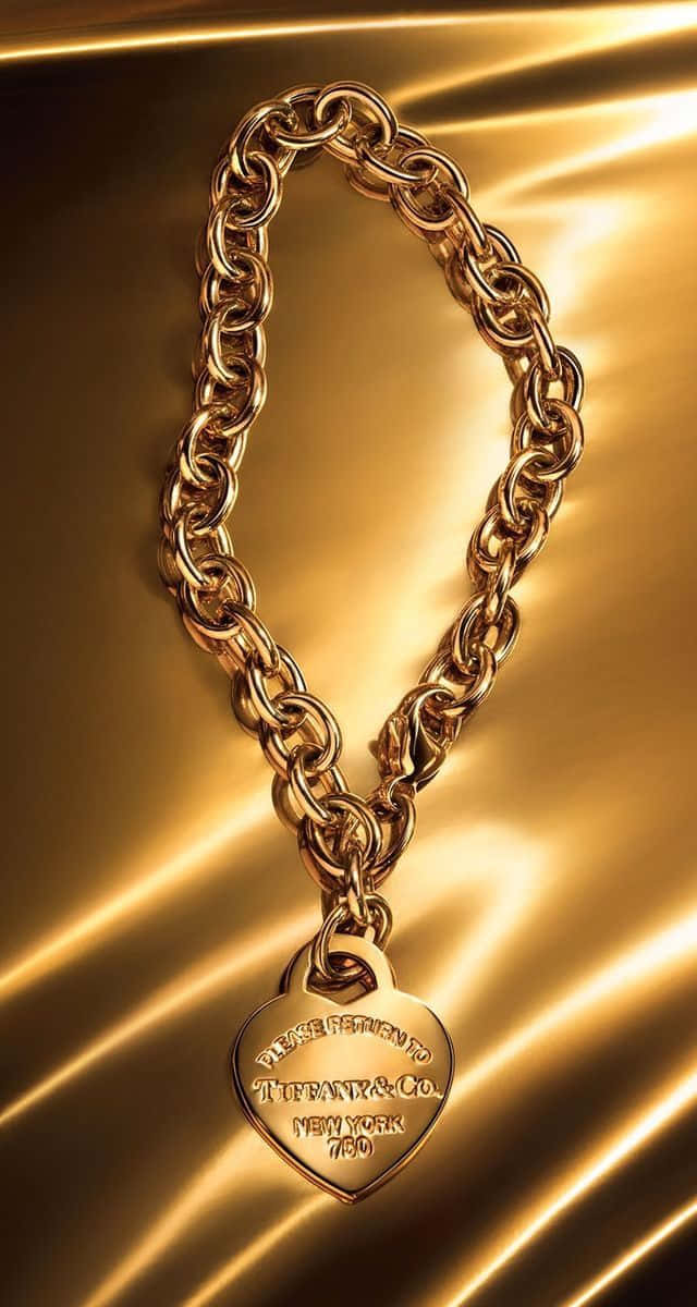 A Gold Chain Bracelet With A Heart On It Background
