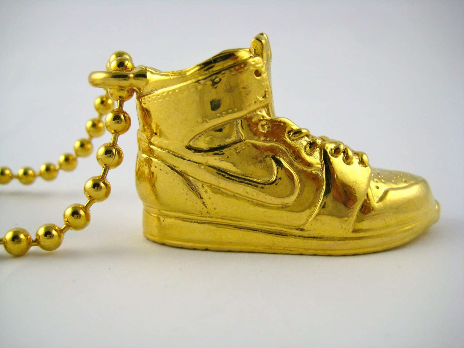 A Gold Nike Shoe With A Chain On It