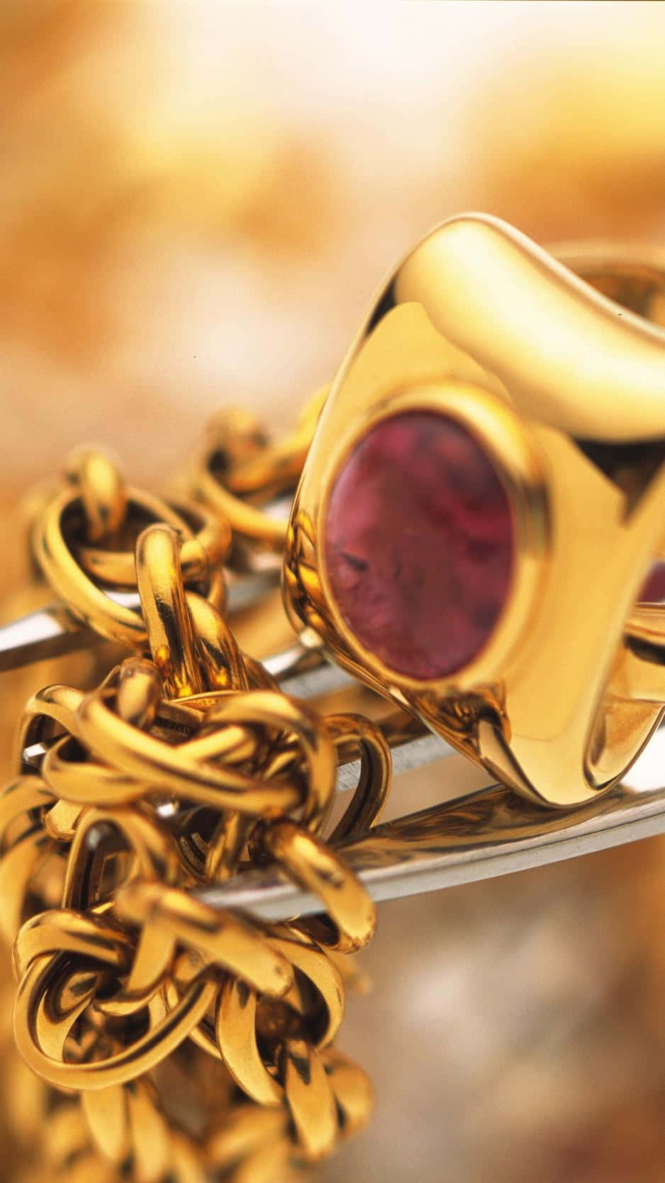 A Gold Ring With A Pink Stone Background