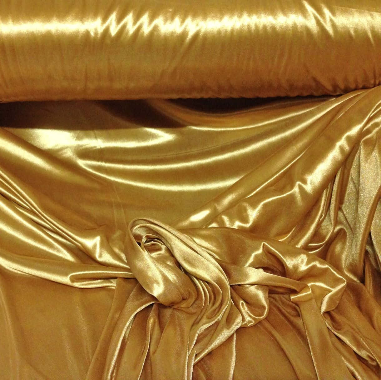 A Gold Satin Fabric Is Laying On A Table Background