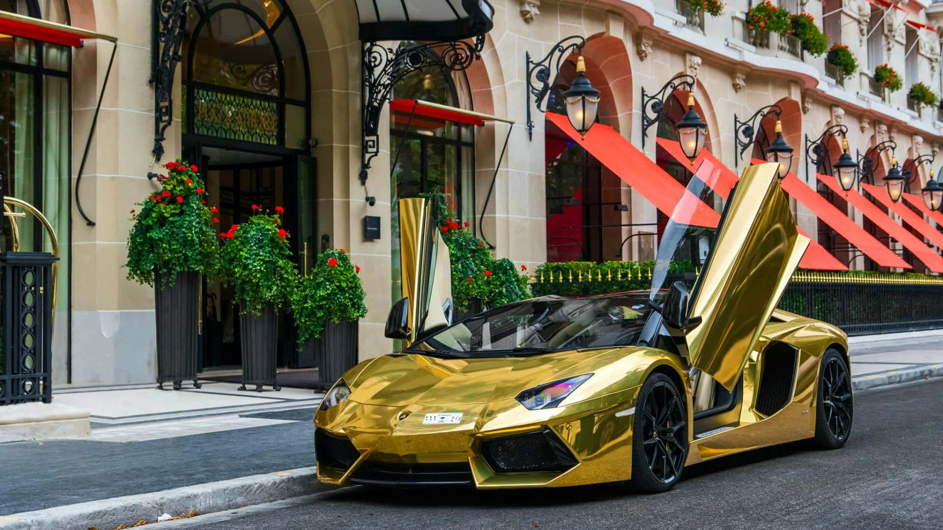 A Gold Sports Car Parked In Front Of A Hotel Background