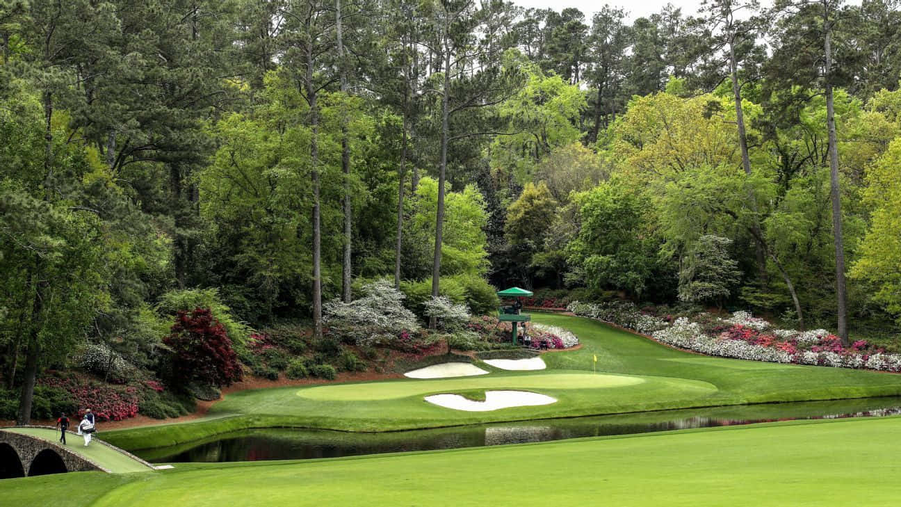 A Golf Course With A Pond And Trees Background