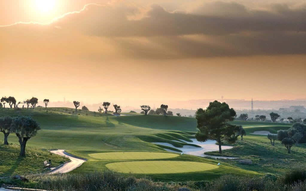 A Golf Course With Trees And A Sunset Background