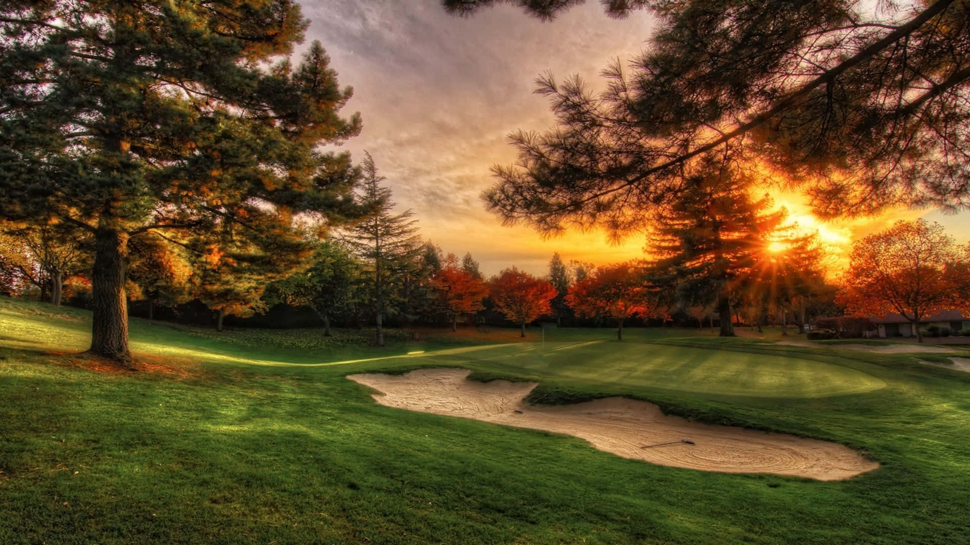 A Golfer Swings His Club With A Beautiful Golf Course In The Background.