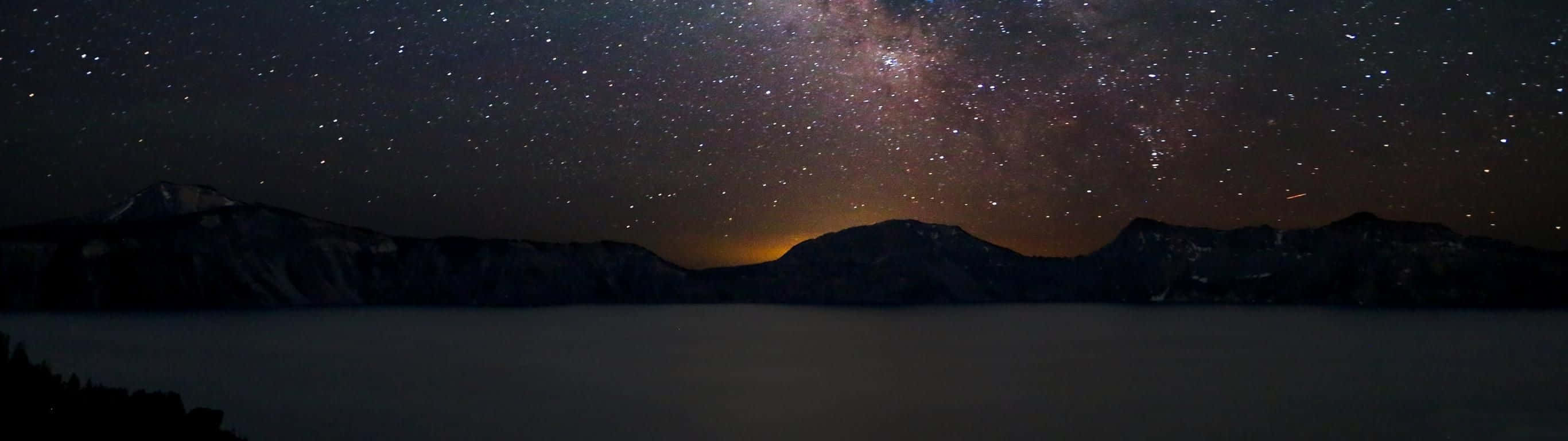 A Gorgeous Night Sky Over A Lake Background