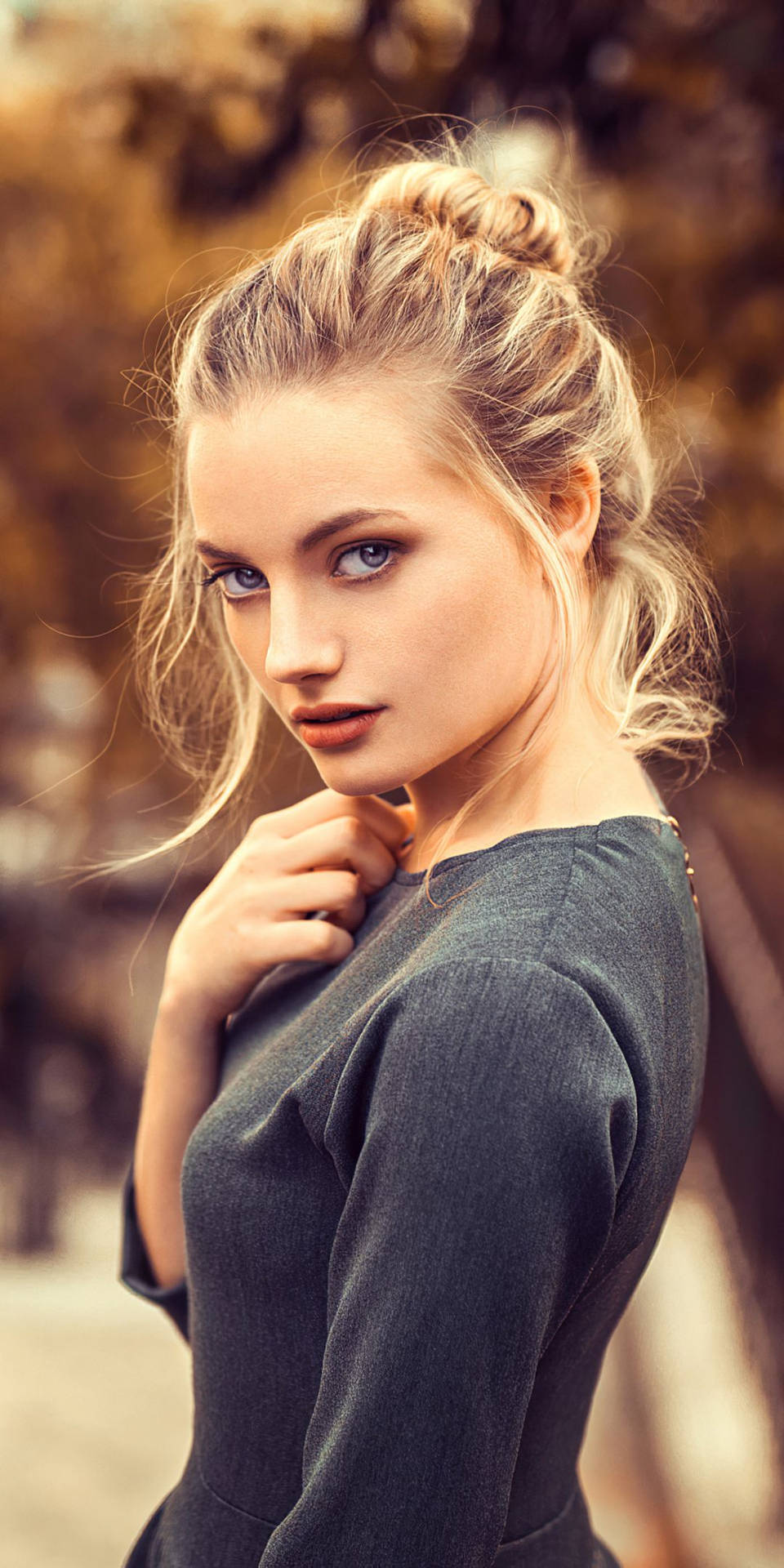 A Graceful Blonde Woman With Her Hair Tied In A Chic Bun Background