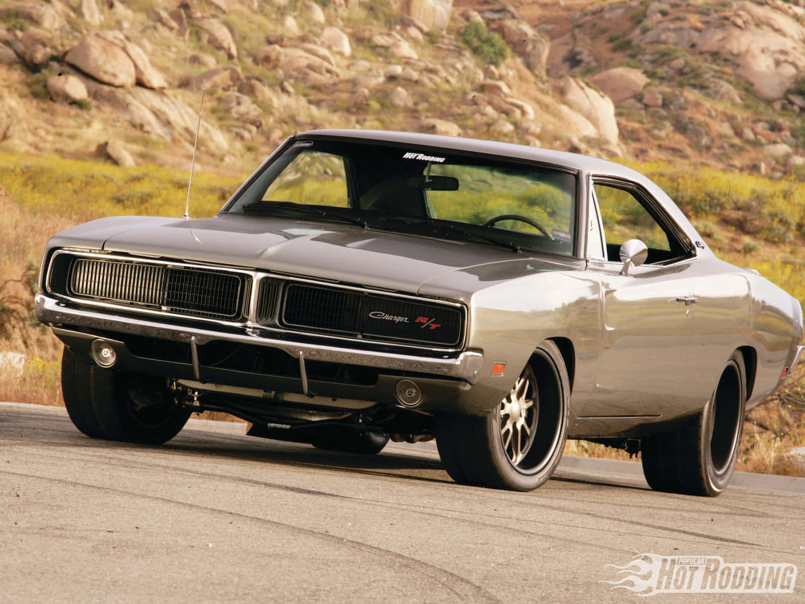 A Gray Muscle Car Driving Down A Road