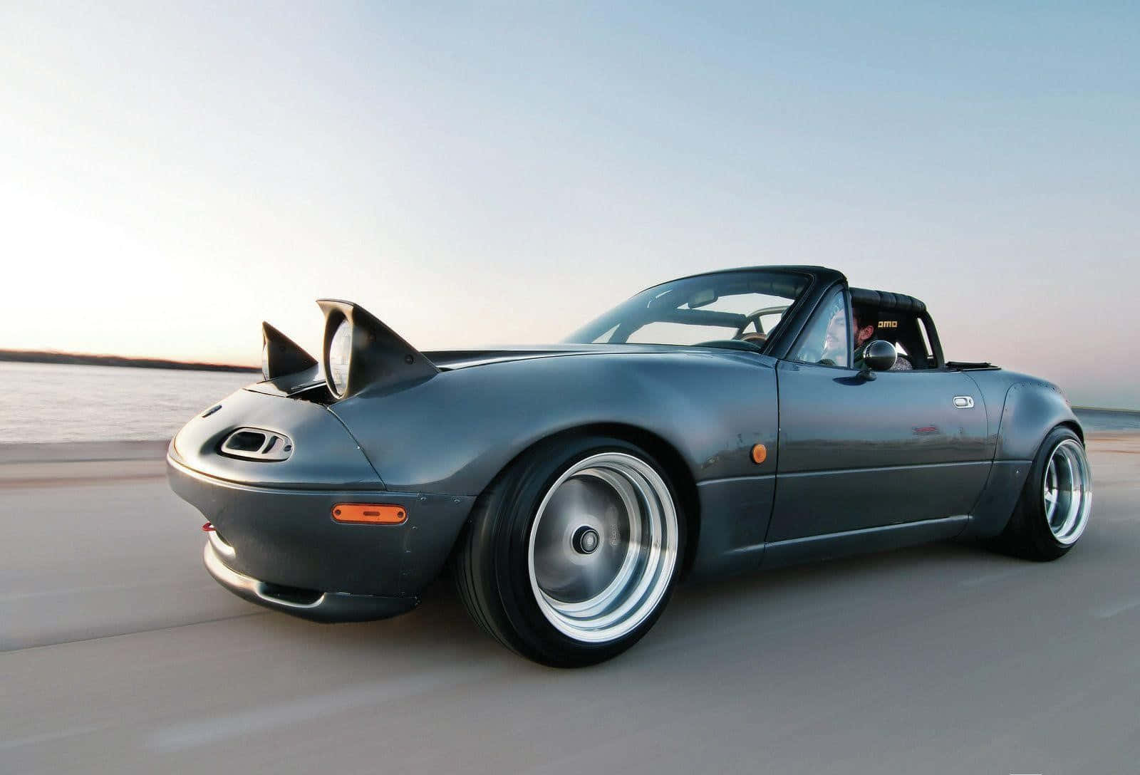 A Gray Sports Car Driving Down The Road